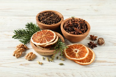 Photo of Different spices, dried orange slices and fir tree branches on white wooden table. Christmas season