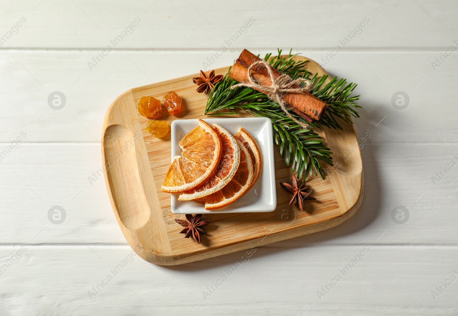 Photo of Different spices, dried orange slices and fir tree branches on white wooden table, flat lay. Christmas season