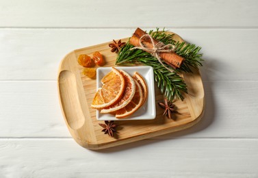 Photo of Different spices, dried orange slices and fir tree branches on white wooden table, flat lay. Christmas season