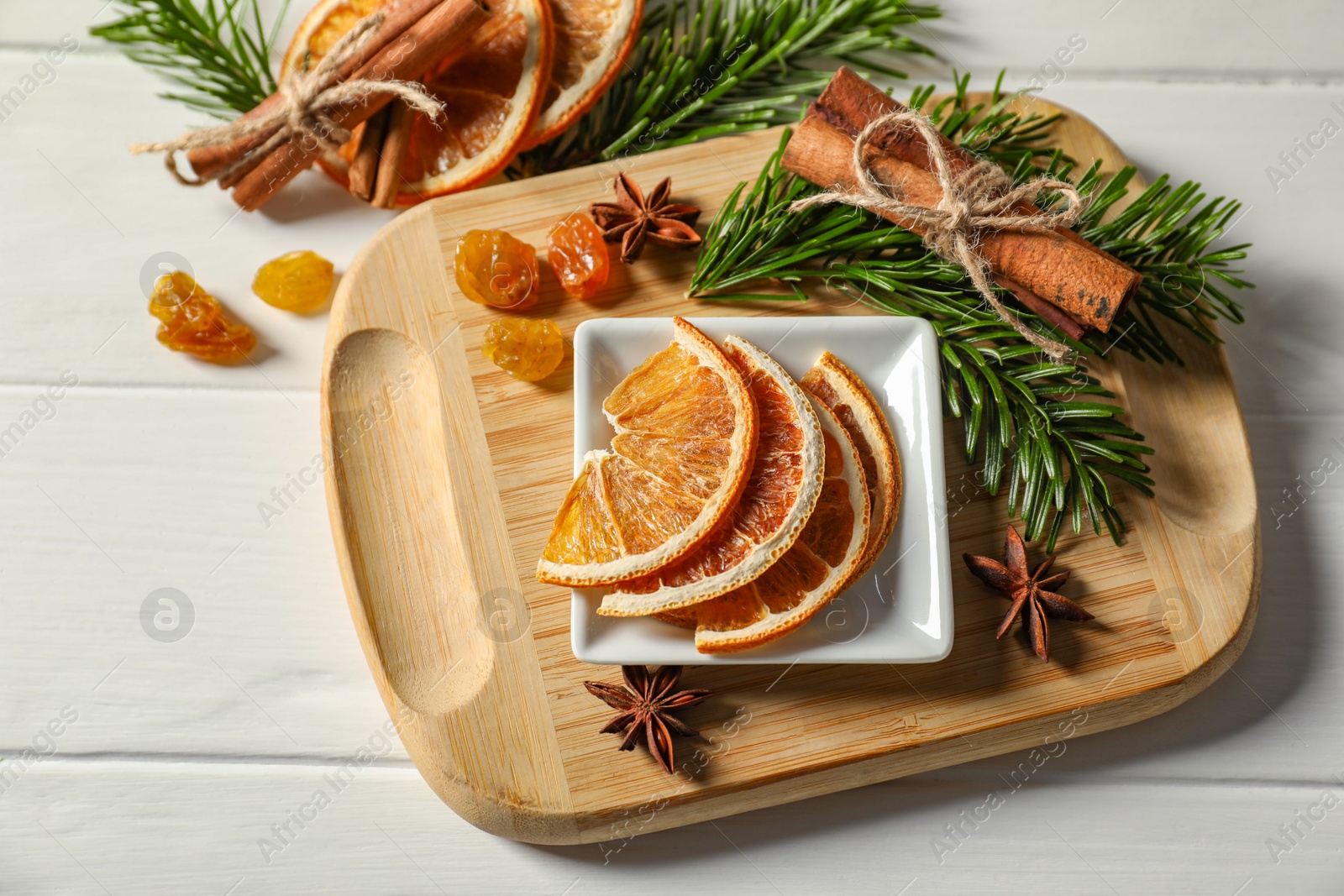 Photo of Different spices, dried orange slices and fir tree branches on white wooden table, above view. Christmas season