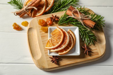 Photo of Different spices, dried orange slices and fir tree branches on white wooden table, above view. Christmas season