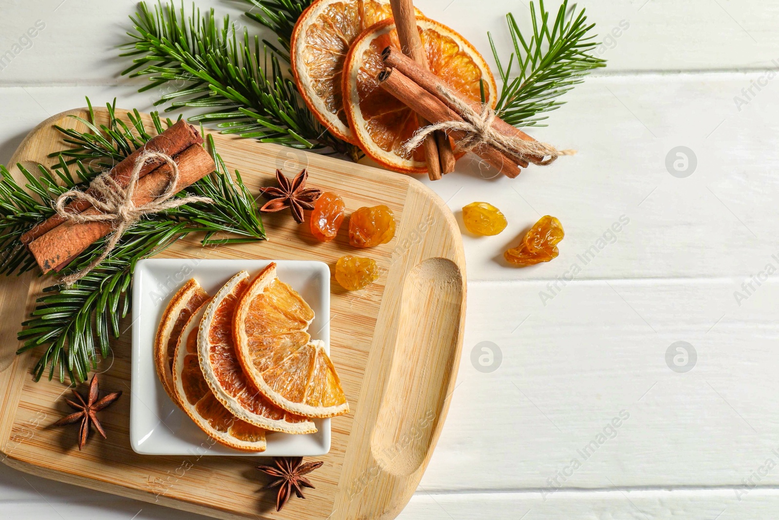 Photo of Different spices, dried orange slices and fir tree branches on white wooden table, flat lay with space for text. Christmas season