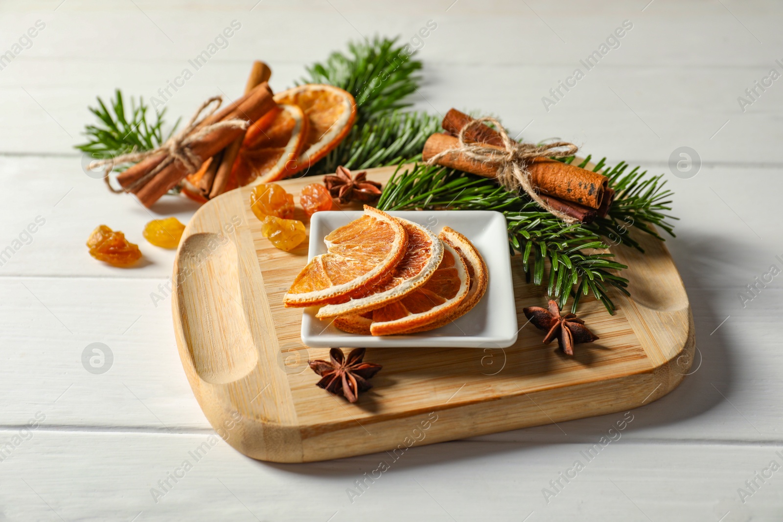 Photo of Different spices, dried orange slices and fir tree branches on white wooden table. Christmas season