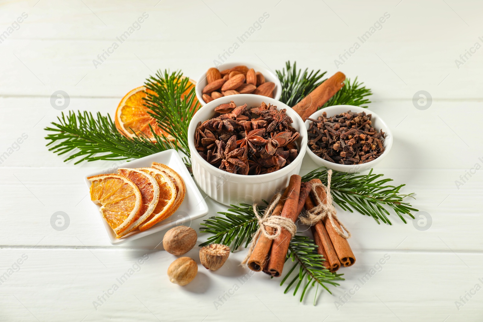 Photo of Different spices, dried orange slices and fir tree branches on white wooden table. Christmas season