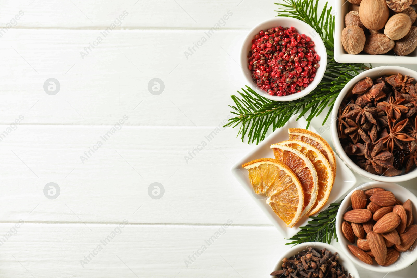 Photo of Different spices, dried orange slices and fir tree branches on white wooden table, flat lay with space for text. Christmas season