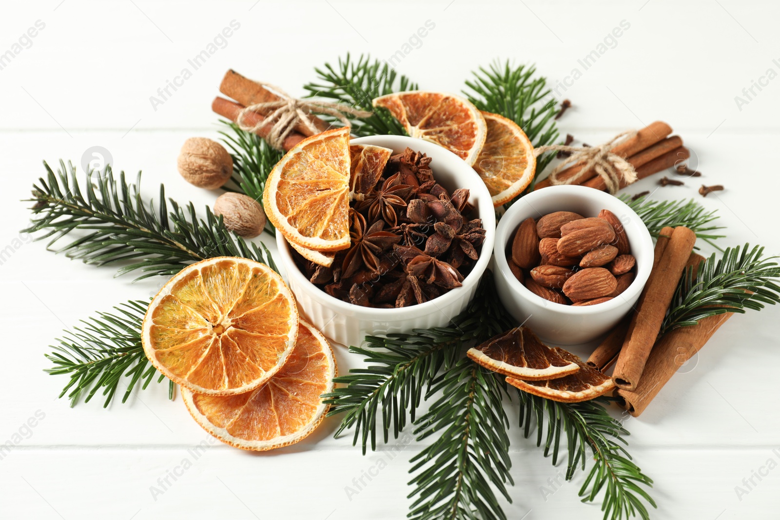 Photo of Different spices, dried orange slices and fir tree branches on white wooden table. Christmas season