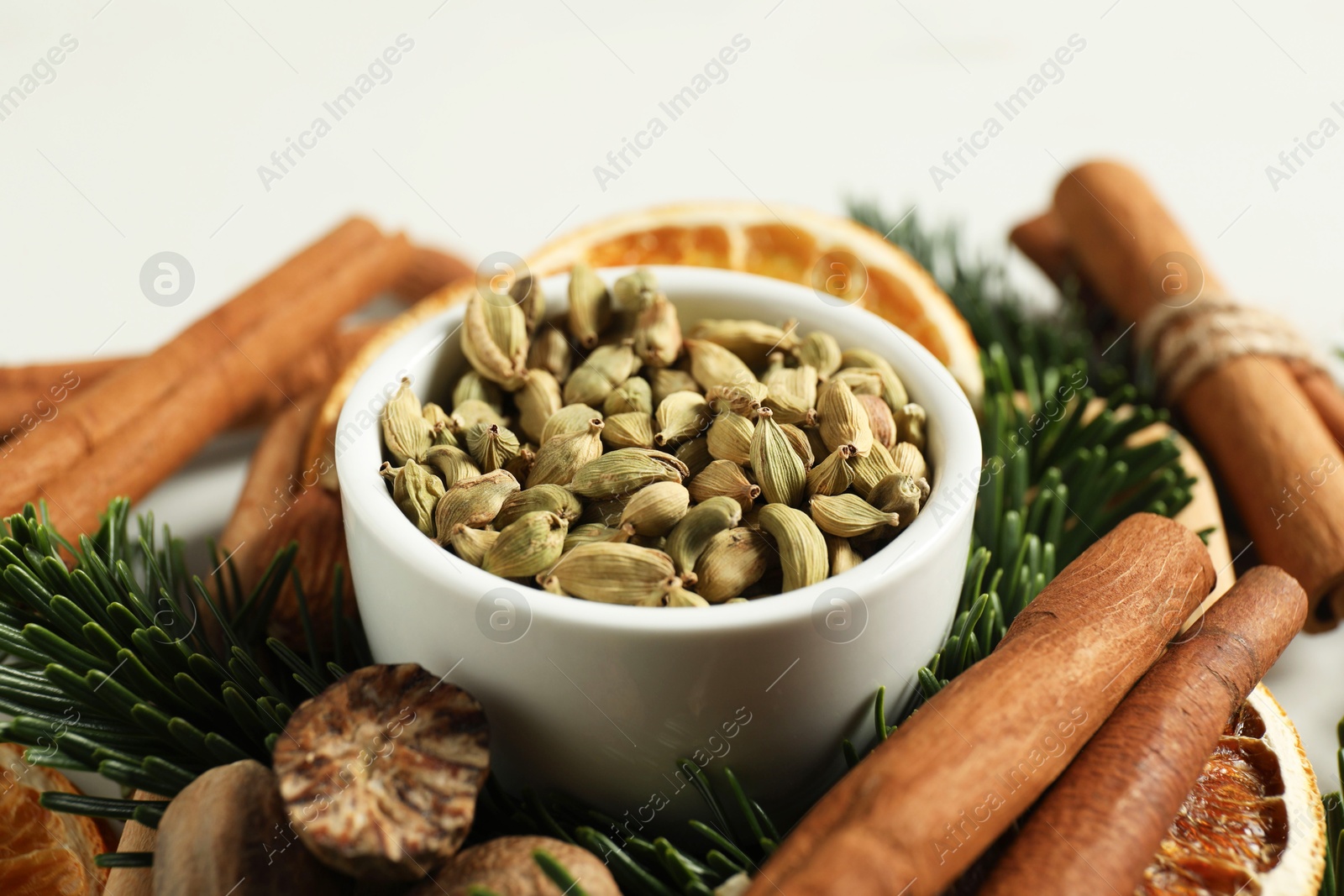 Photo of Different spices, dried orange slices and fir tree branches on white table, closeup. Christmas season