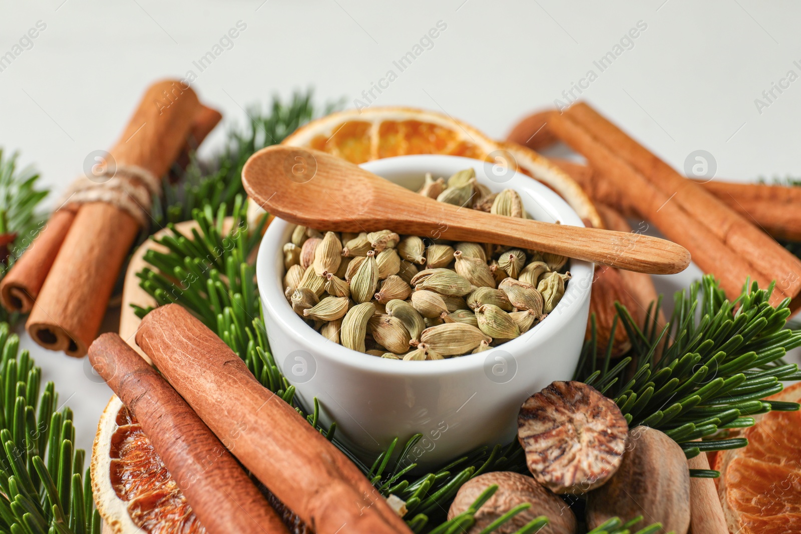 Photo of Different spices, dried orange slices and fir tree branches on white table, closeup. Christmas season