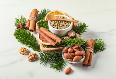 Photo of Different spices, dried orange slices and fir tree branches on white marble table. Christmas season