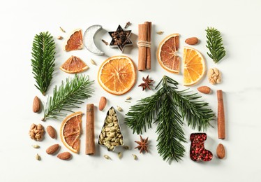 Photo of Different spices, dried orange slices and fir tree branches on white marble table, flat lay. Christmas season