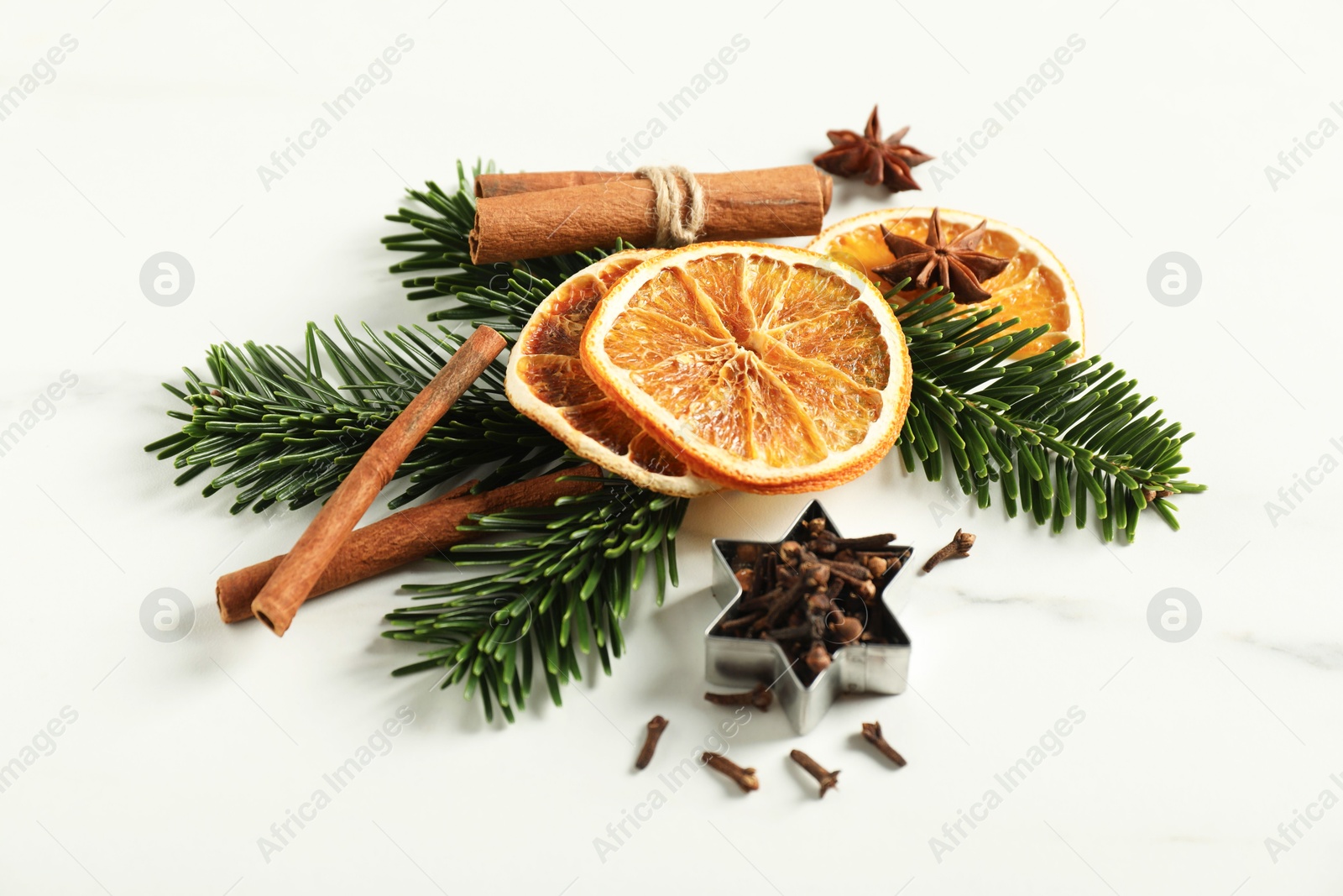 Photo of Different spices, dried orange slices and fir tree branches on white marble table. Christmas season