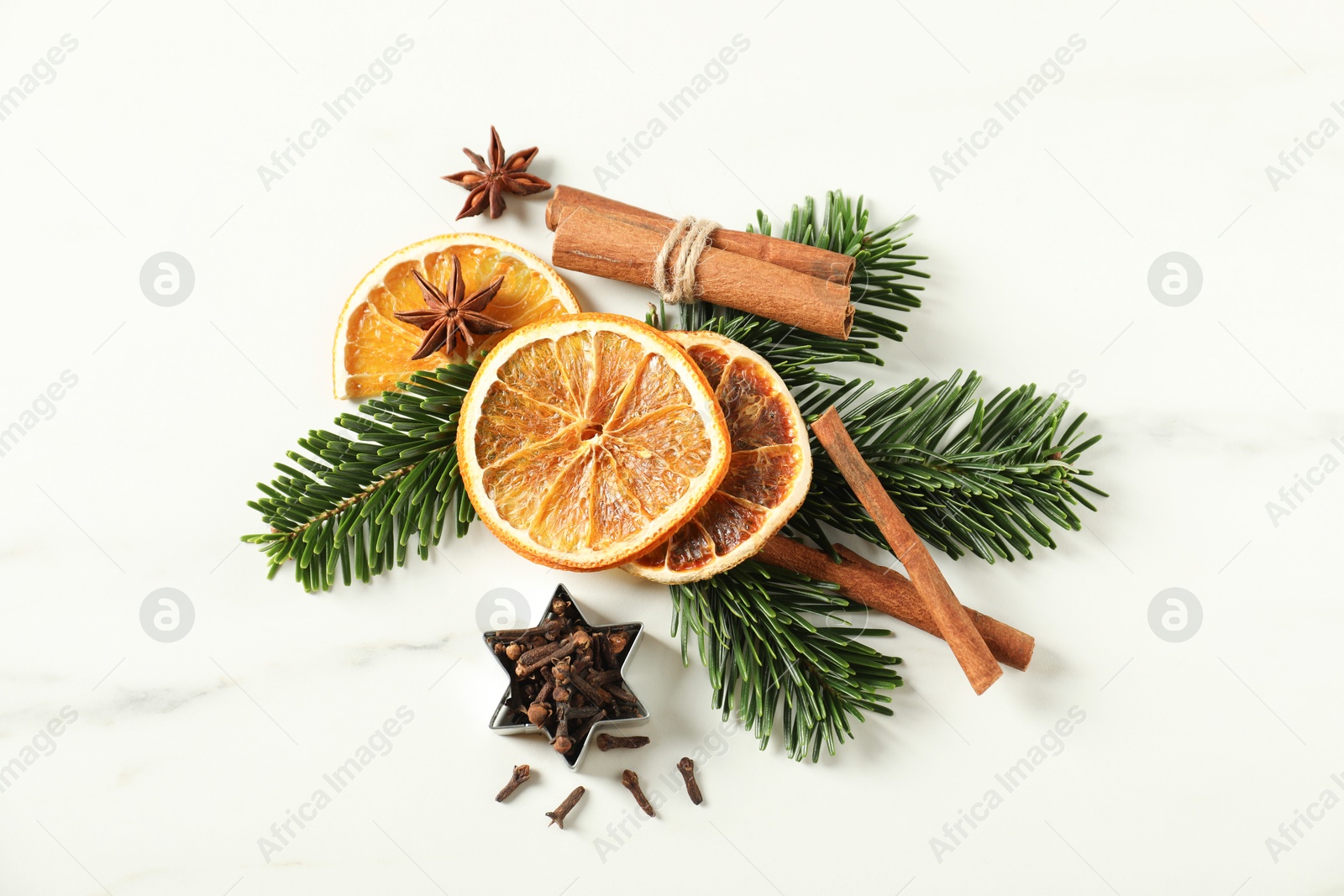 Photo of Different spices, dried orange slices and fir tree branches on white marble table, flat lay. Christmas season