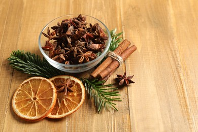 Photo of Different spices, dried orange slices and fir tree branches on wooden table, space for text. Christmas season