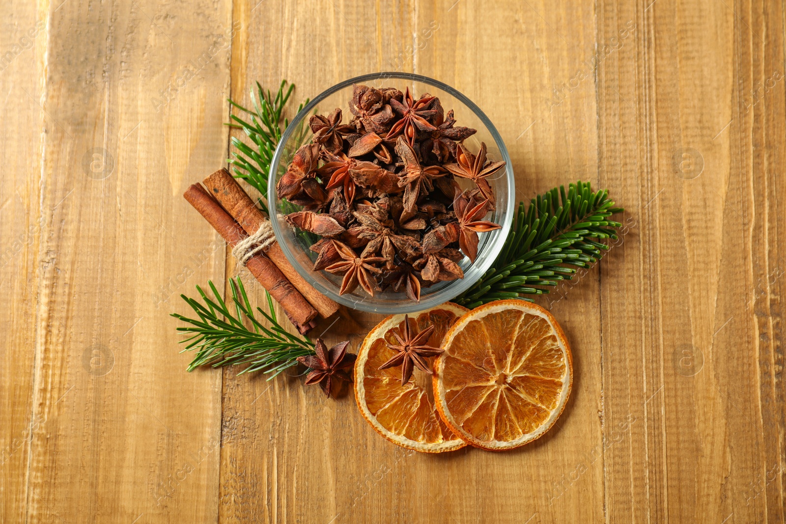 Photo of Different spices, dried orange slices and fir tree branches on wooden table, flat lay. Christmas season