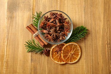 Photo of Different spices, dried orange slices and fir tree branches on wooden table, flat lay. Christmas season