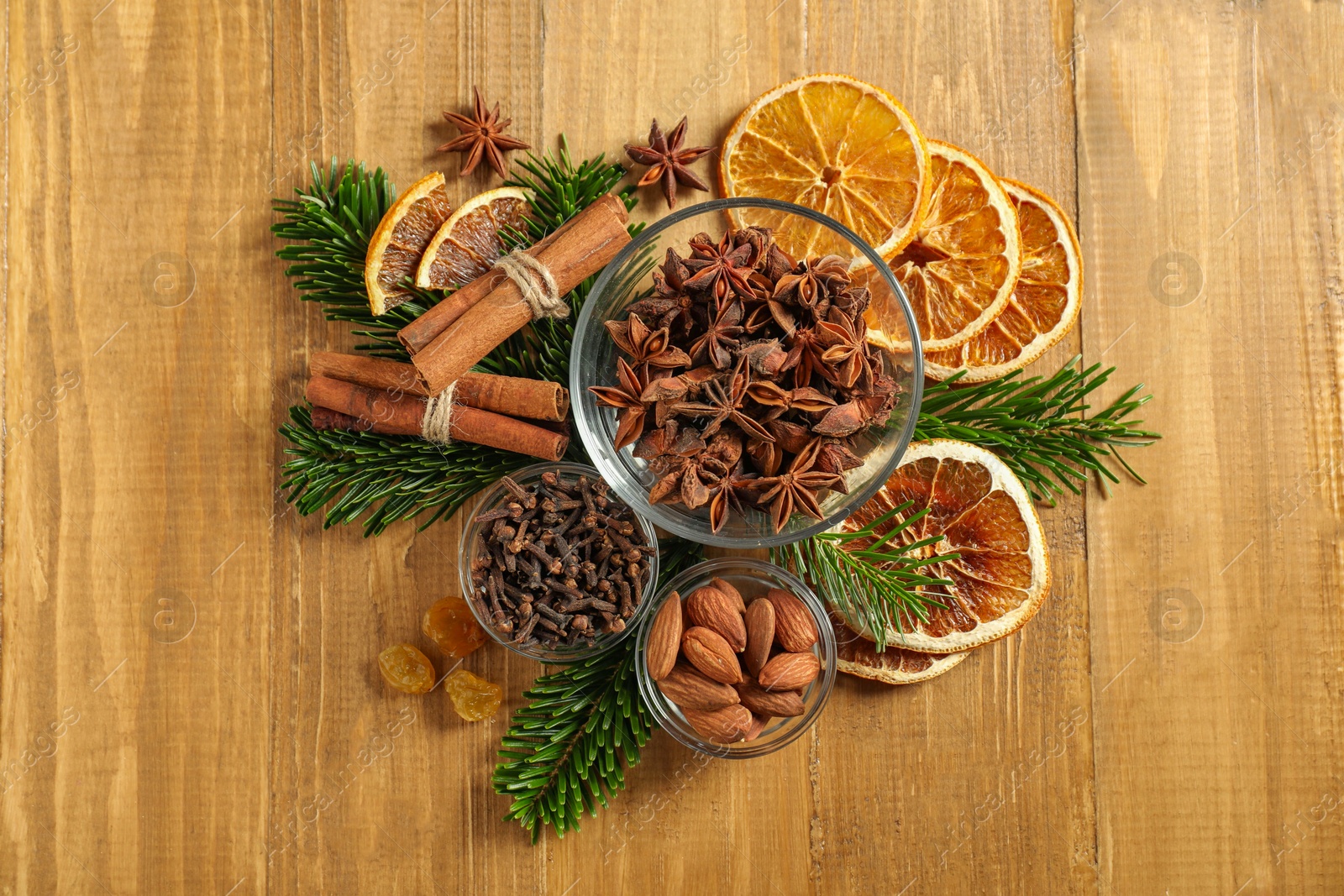 Photo of Different spices, dried orange slices and fir tree branches on wooden table, flat lay. Christmas season