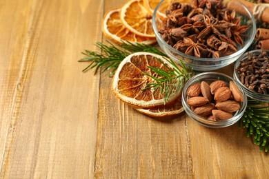 Photo of Different spices, dried orange slices and fir tree branches on wooden table, closeup with space for text. Christmas season