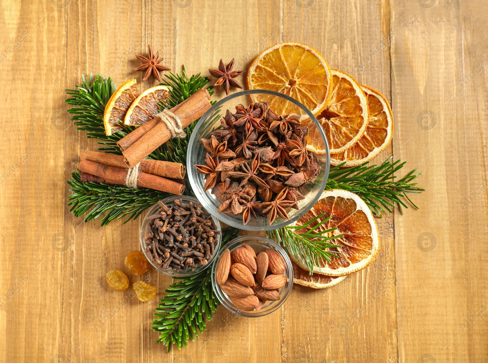 Photo of Different spices, dried orange slices and fir tree branches on wooden table, flat lay. Christmas season