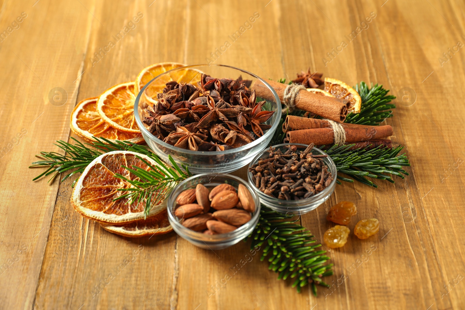 Photo of Different spices, dried orange slices and fir tree branches on wooden table. Christmas season