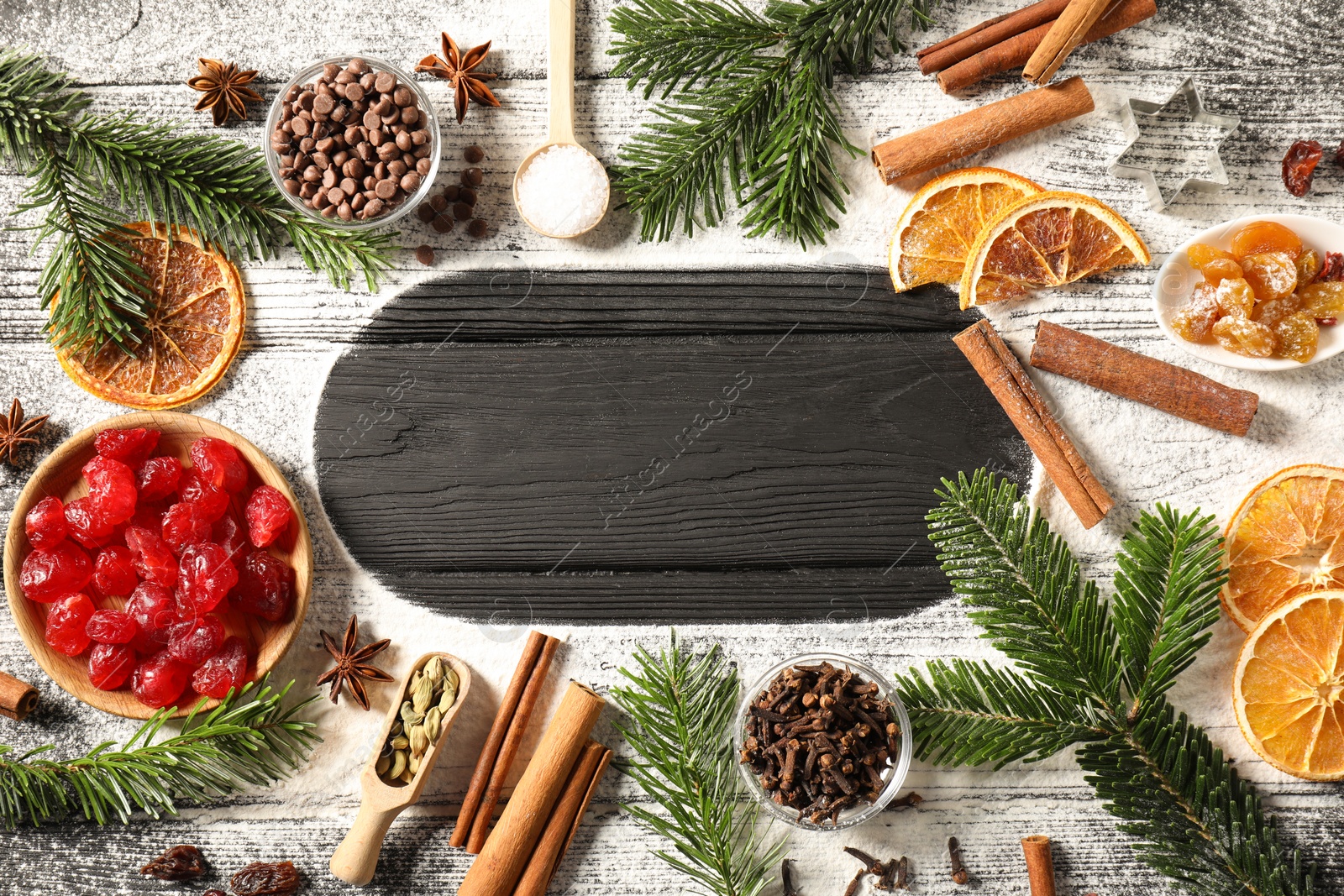 Photo of Frame of different aromatic spices and fir tree branches on wooden table, flat lay with space for text. Christmas season