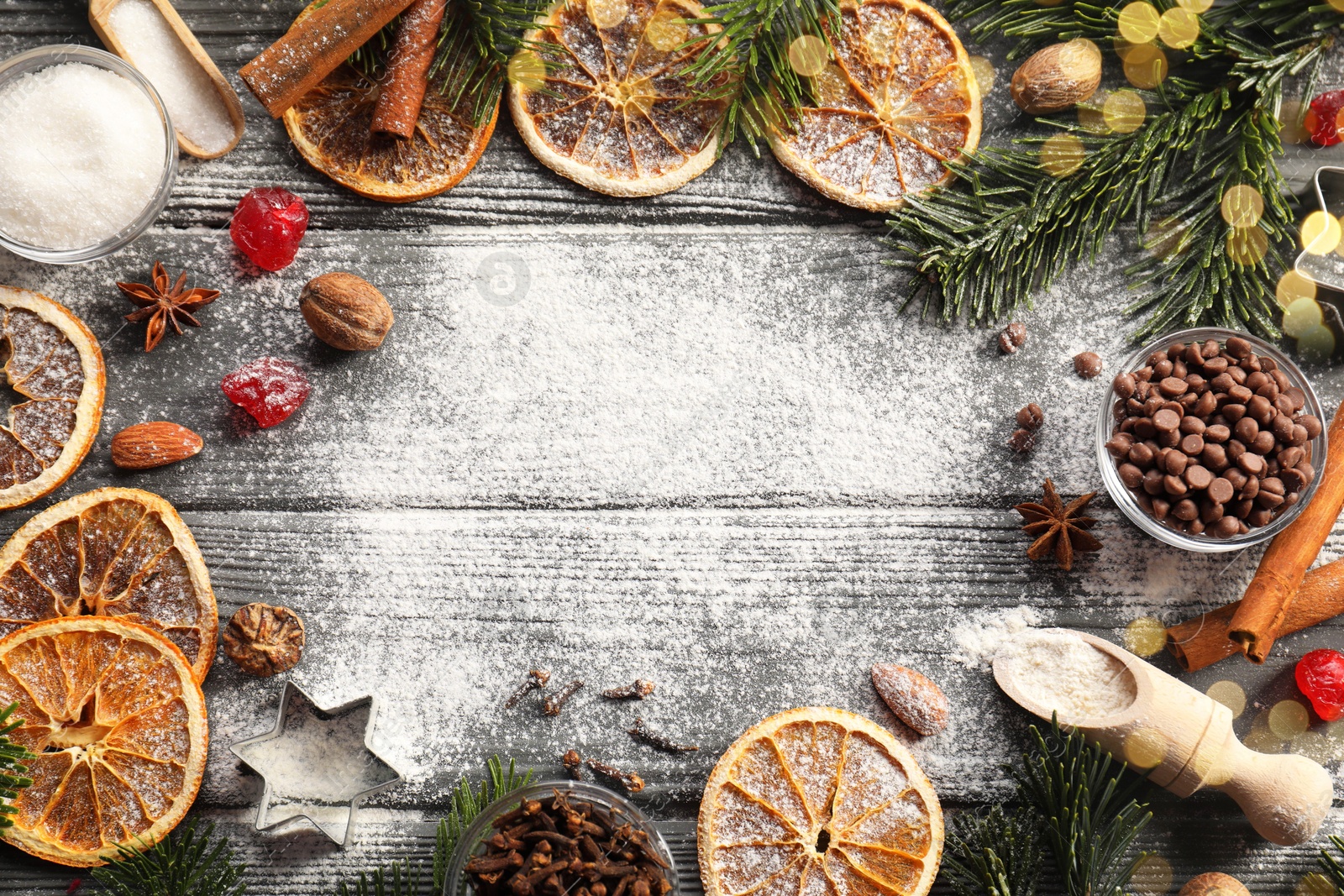 Photo of Frame of different aromatic spices and fir tree branches on wooden table, flat lay with space for text. Christmas season