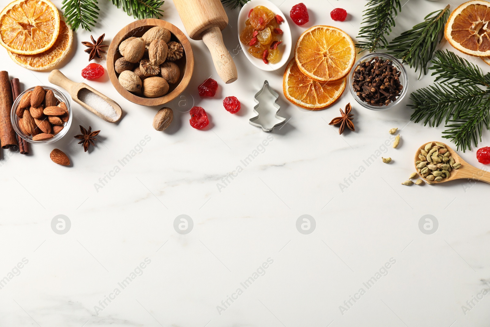 Photo of Different aromatic spices and fir tree branches on white table, flat lay with space for text. Christmas season