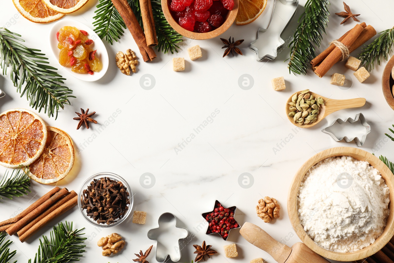 Photo of Frame of different aromatic spices and fir tree branches on white table, flat lay with space for text. Christmas season