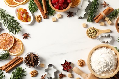 Photo of Frame of different aromatic spices and fir tree branches on white table, flat lay with space for text. Christmas season