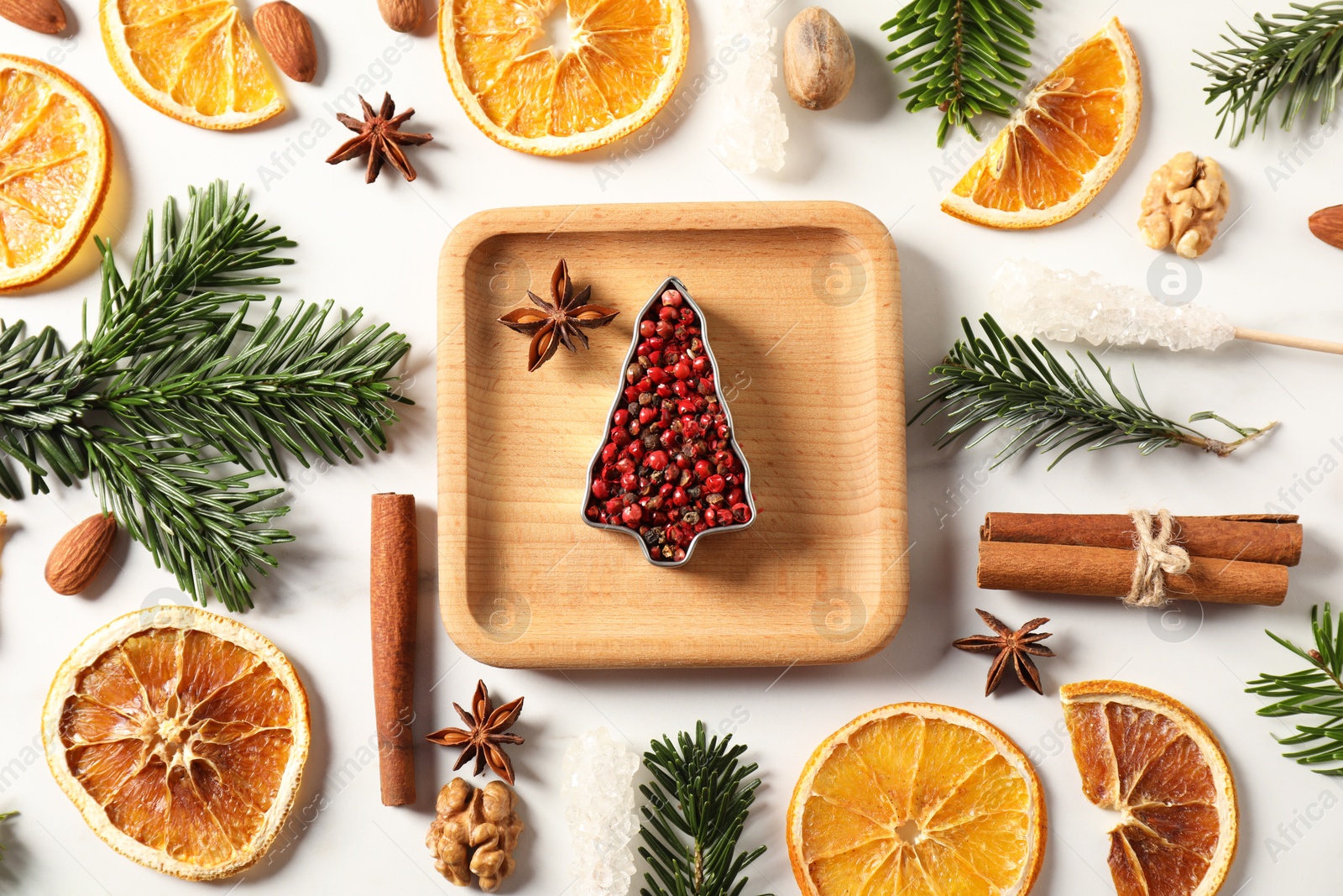 Photo of Different aromatic spices and fir tree branches on white table, flat lay. Christmas season