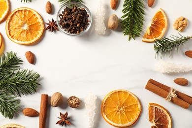 Photo of Frame of different aromatic spices and fir tree branches on white table, flat lay with space for text. Christmas season