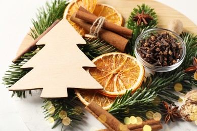 Different aromatic spices and fir tree branches on white table, closeup. Christmas season