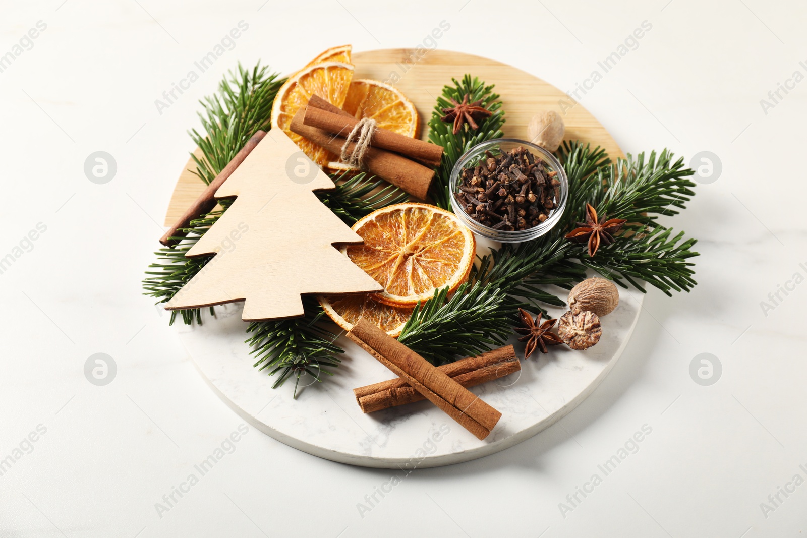 Photo of Different aromatic spices and fir tree branches on white table. Christmas season