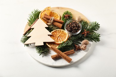 Photo of Different aromatic spices and fir tree branches on white table. Christmas season