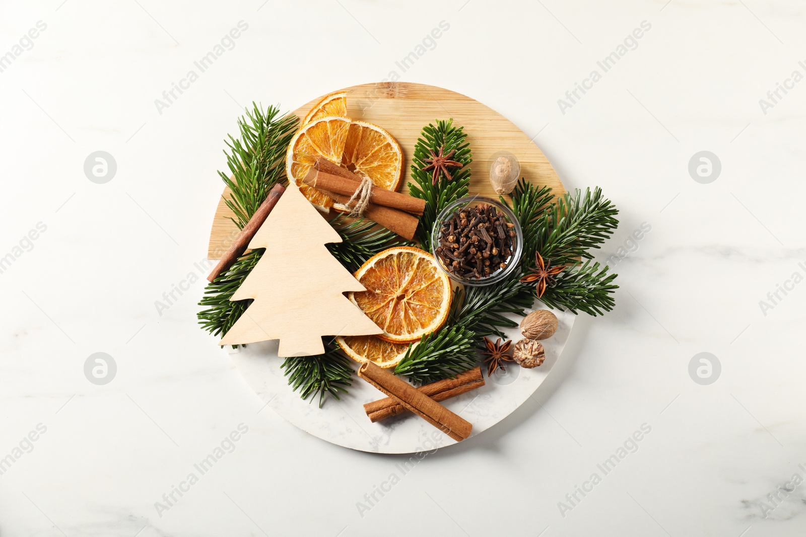 Photo of Different aromatic spices and fir tree branches on white table, top view. Christmas season