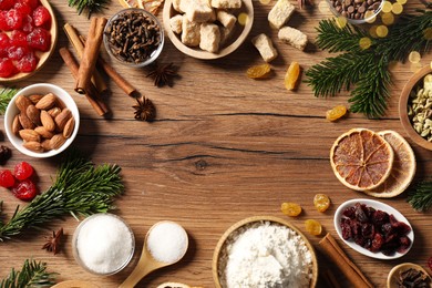 Photo of Frame of different aromatic spices and fir tree branches on wooden table, flat lay with space for text. Christmas season