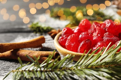 Photo of Candied cranberries, cinnamon sticks and fir tree branch on wooden table, closeup. Christmas season