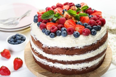 Photo of Delicious chocolate sponge cake with berries served on light table, closeup