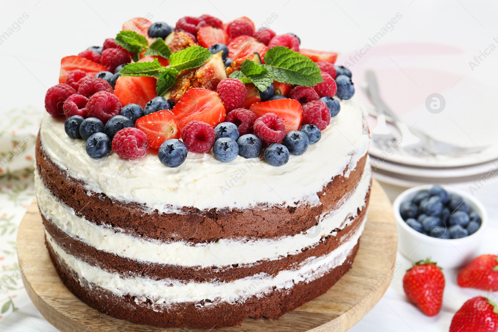 Photo of Delicious chocolate sponge cake with berries served on light table, closeup