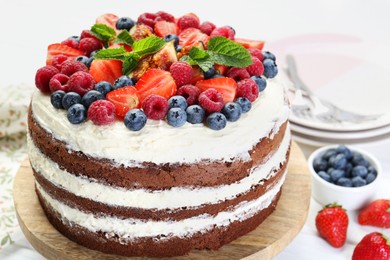 Photo of Delicious chocolate sponge cake with berries served on light table, closeup