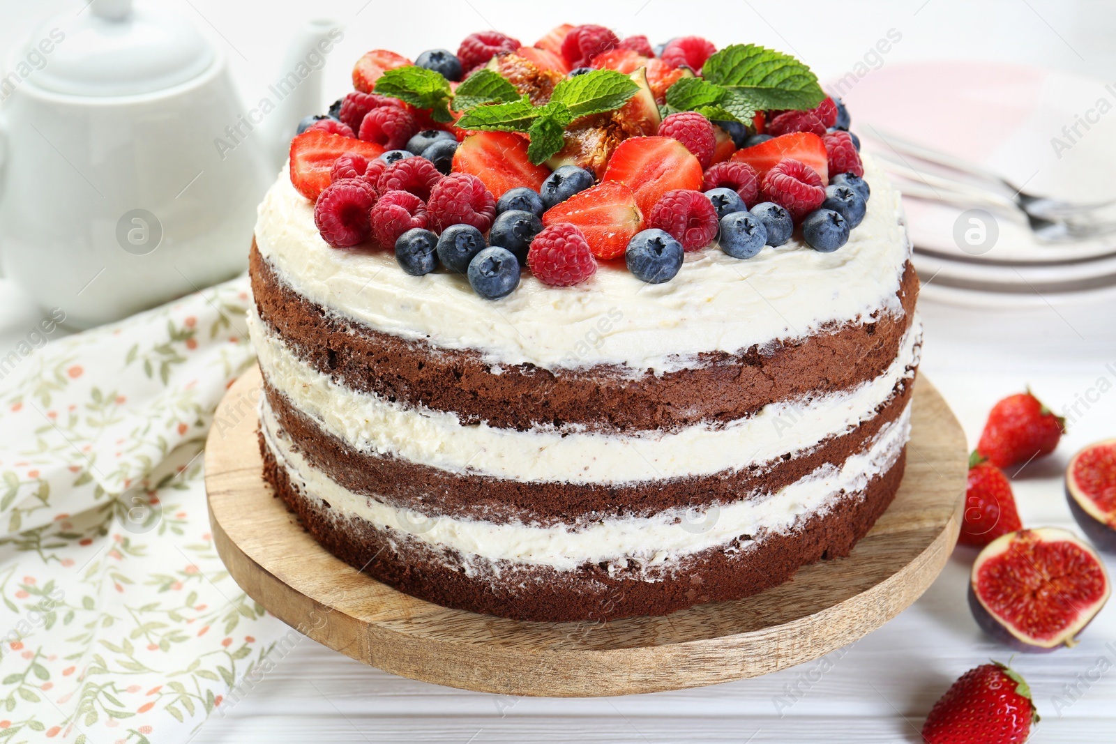 Photo of Delicious chocolate sponge cake with berries served on light table, closeup