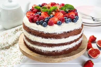 Photo of Delicious chocolate sponge cake with berries served on light table, closeup