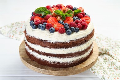 Photo of Delicious chocolate sponge cake with berries on light table, closeup