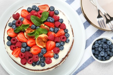 Photo of Delicious chocolate sponge cake with berries served on light table, flat lay