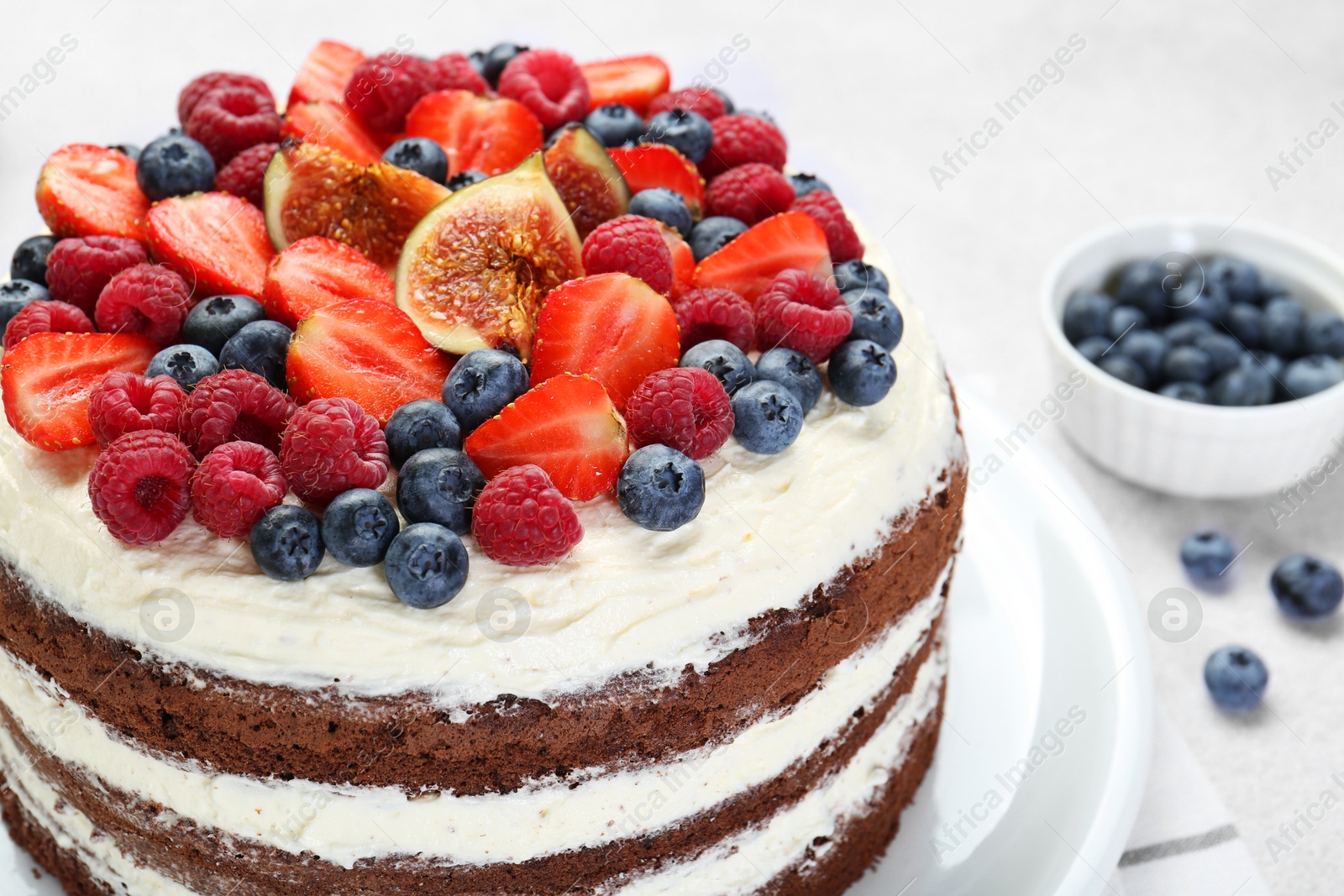 Photo of Delicious chocolate sponge cake with berries on light table, closeup