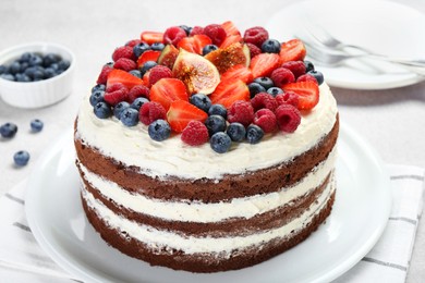 Photo of Delicious chocolate sponge cake with berries served on light table, closeup