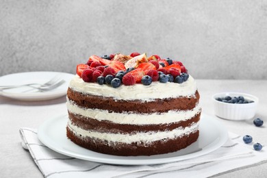 Photo of Delicious chocolate sponge cake with berries on light table