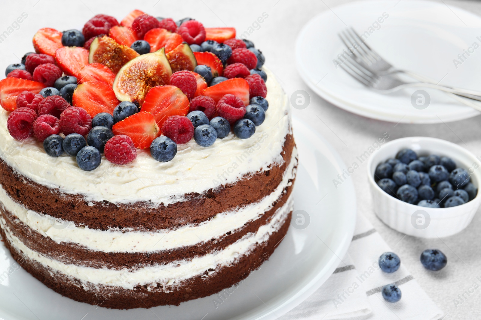 Photo of Delicious chocolate sponge cake with berries served on light table, closeup