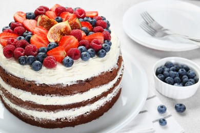 Delicious chocolate sponge cake with berries served on light table, closeup