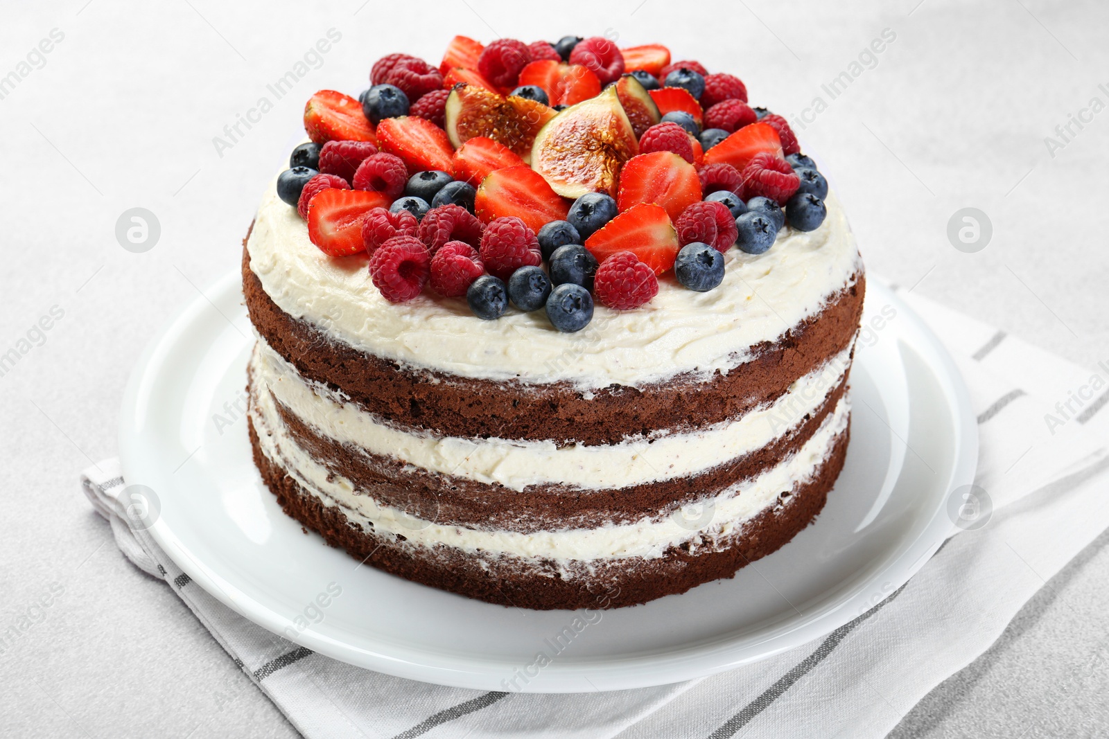 Photo of Delicious chocolate sponge cake with berries on light table, closeup