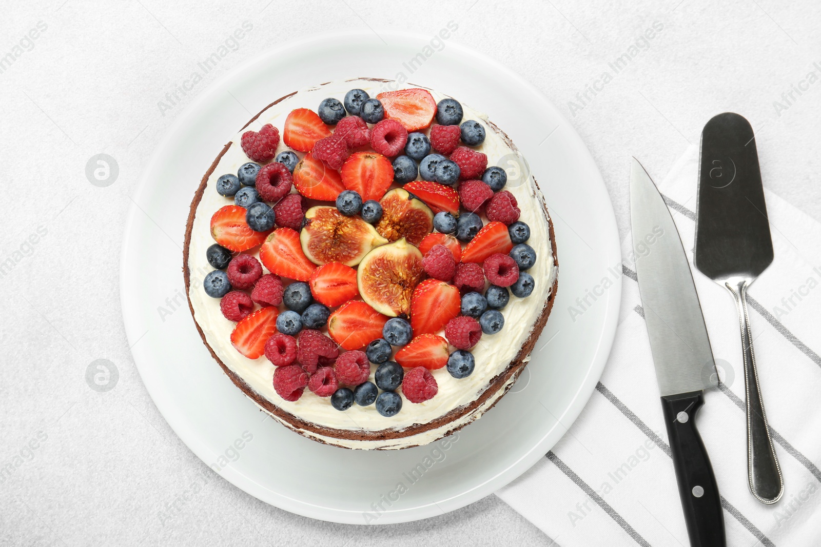 Photo of Delicious chocolate sponge cake with berries, server and knife on light table, top view